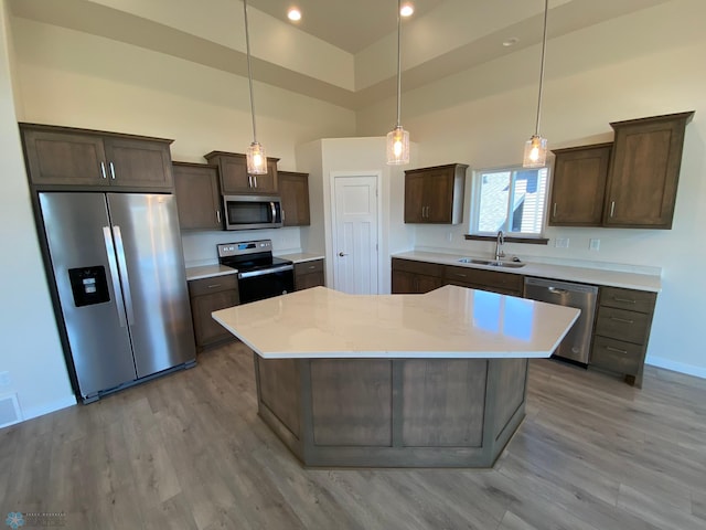 kitchen featuring a sink, dark brown cabinetry, a towering ceiling, stainless steel appliances, and baseboards