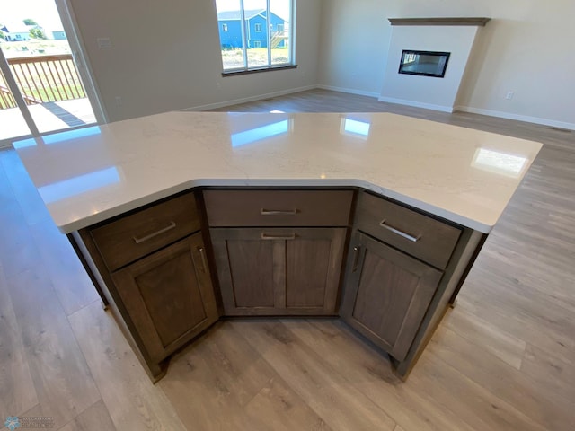kitchen featuring a center island, a glass covered fireplace, light wood-style floors, and a healthy amount of sunlight