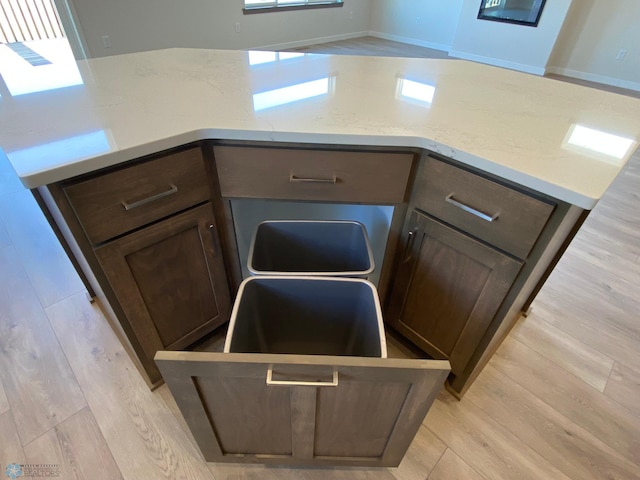 details with light stone countertops, dark brown cabinetry, and light wood-style floors