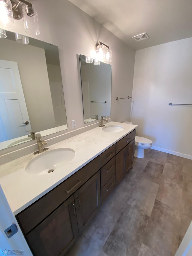 full bathroom with toilet, a sink, visible vents, and double vanity