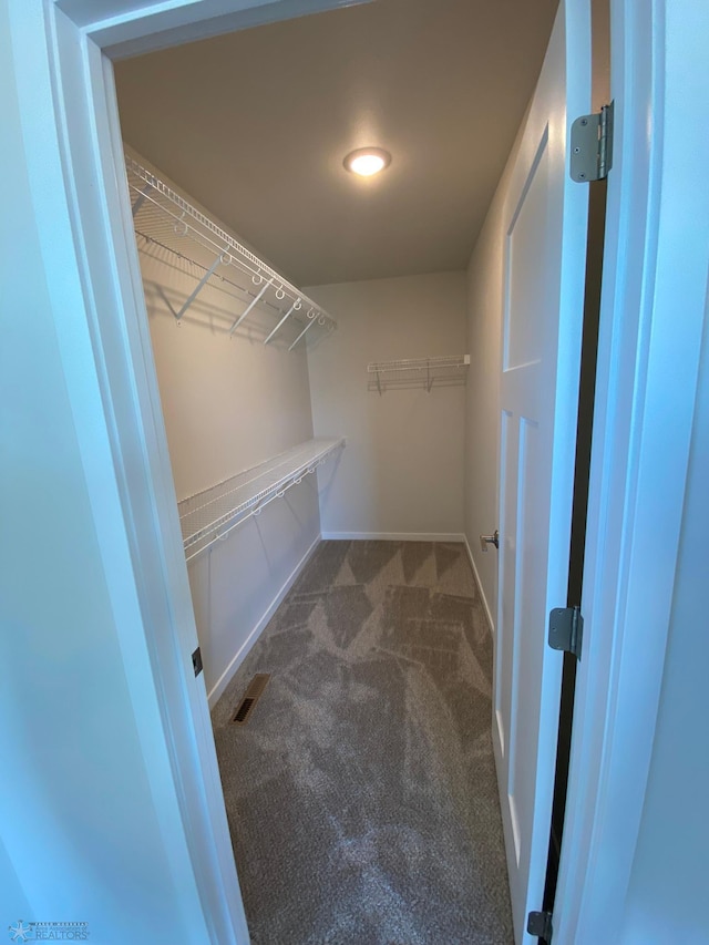 spacious closet featuring dark carpet and visible vents