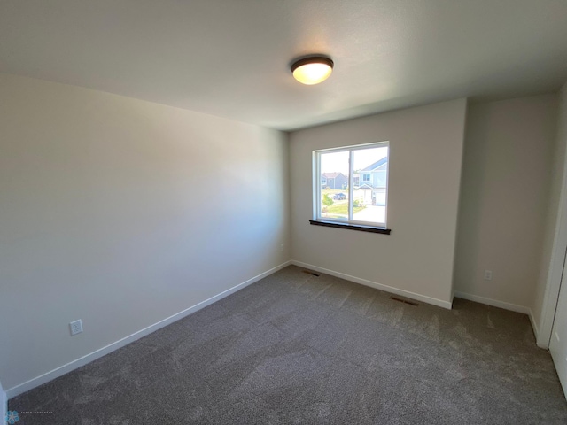 carpeted spare room featuring baseboards and visible vents