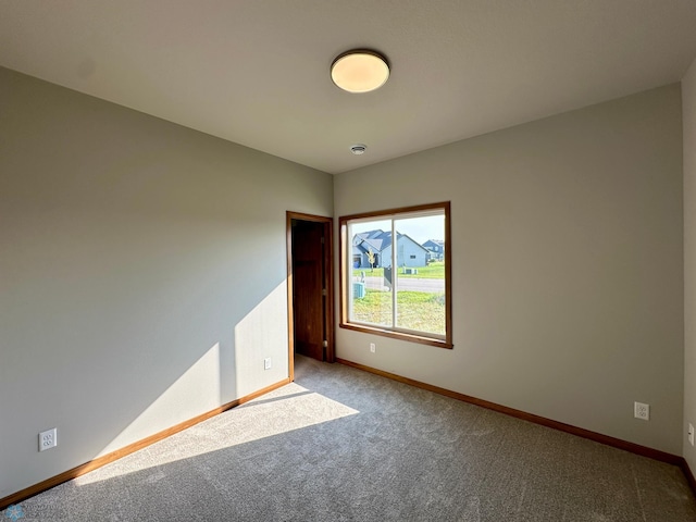 unfurnished room with carpet flooring and baseboards