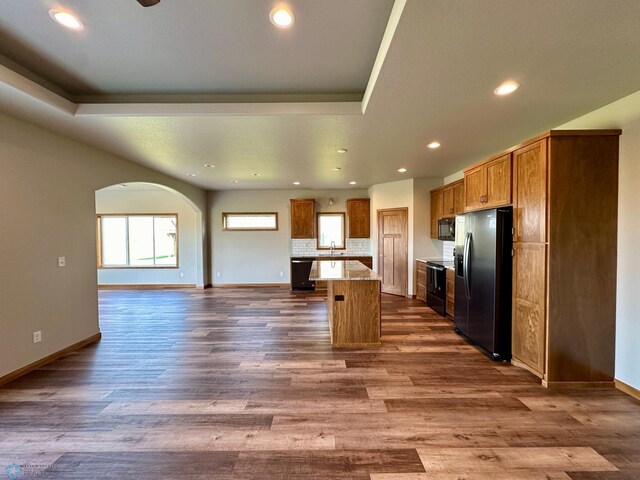 kitchen with a kitchen island, hardwood / wood-style floors, stainless steel fridge with ice dispenser, sink, and decorative backsplash