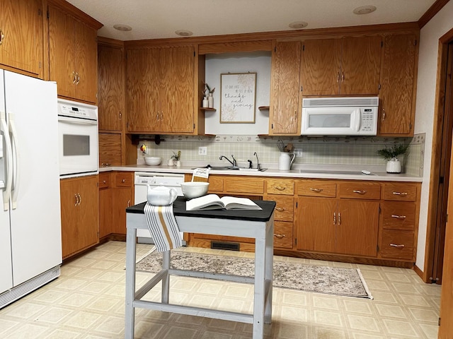 kitchen featuring white appliances, backsplash, and sink