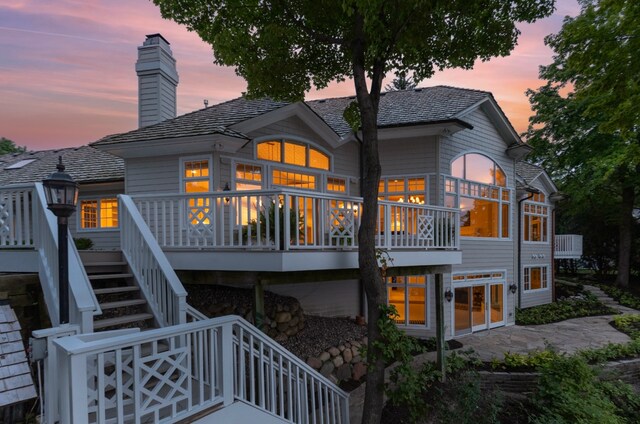 back house at dusk featuring a deck