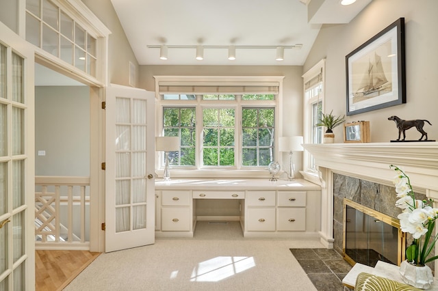 bathroom featuring vanity, french doors, track lighting, a fireplace, and vaulted ceiling