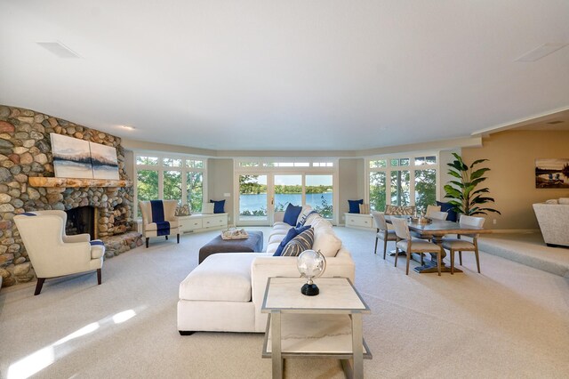 living room with a stone fireplace, light carpet, and french doors