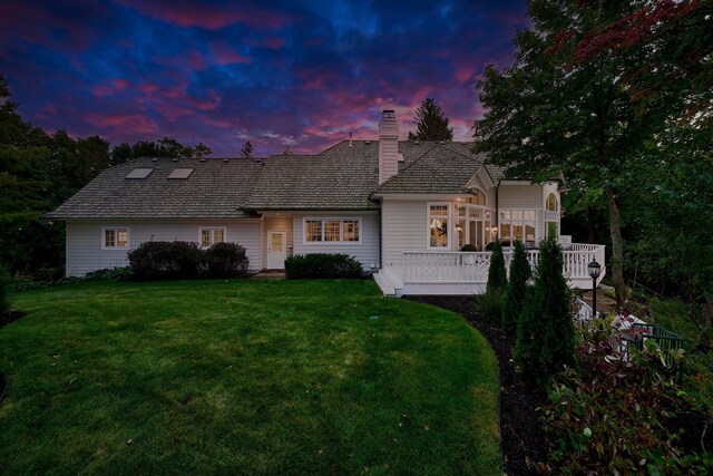 view of front of home with a deck and a lawn