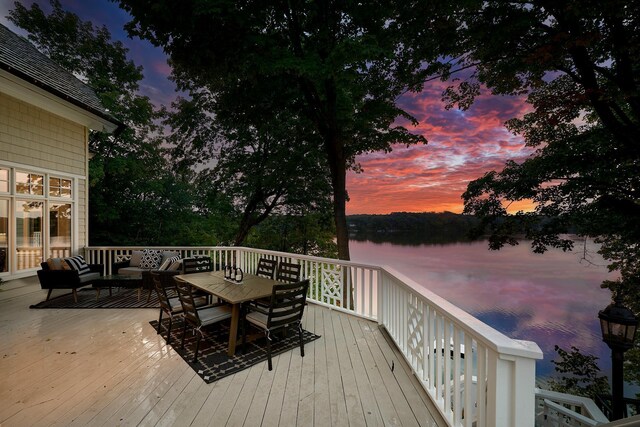 deck at dusk featuring an outdoor hangout area and a water view