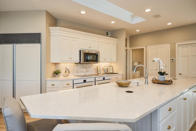 kitchen with a large island, white cabinetry, and light stone countertops