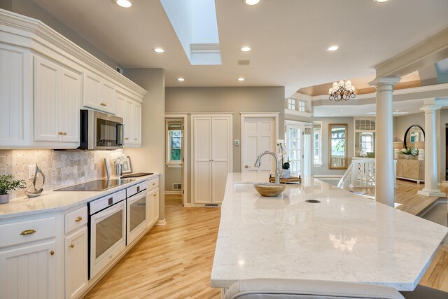 kitchen with white oven, light stone countertops, and an island with sink