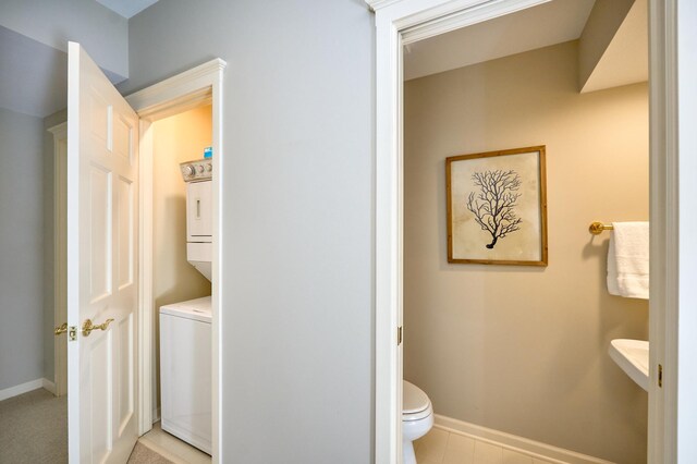 bathroom featuring toilet, tile patterned flooring, and stacked washer and dryer