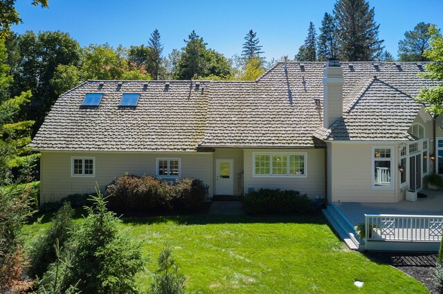 rear view of property featuring a lawn and a deck