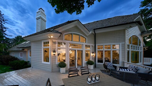 back house at dusk featuring outdoor lounge area and a deck