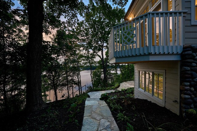 property exterior at dusk featuring a balcony and a water view