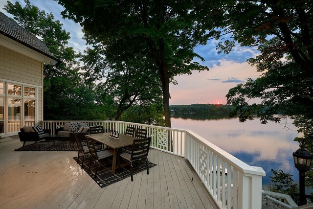 deck at dusk with a water view and an outdoor living space