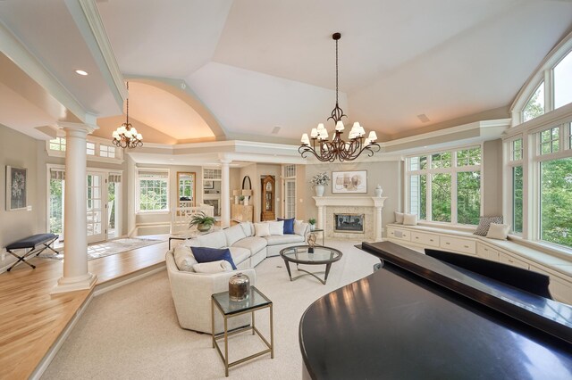 living room with a notable chandelier, plenty of natural light, and decorative columns