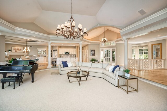 carpeted living room featuring lofted ceiling, a chandelier, decorative columns, and crown molding