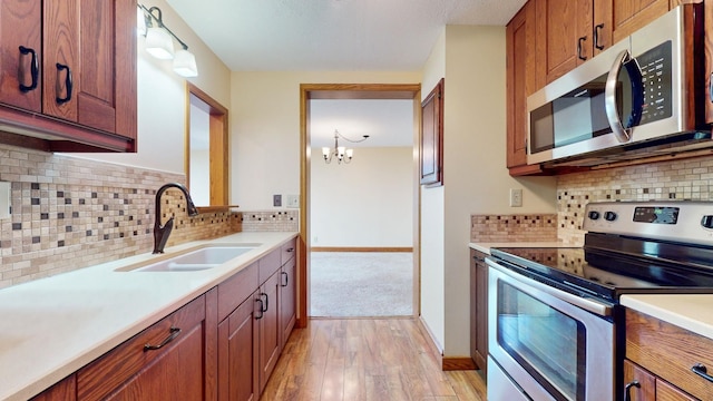 kitchen with tasteful backsplash, appliances with stainless steel finishes, light hardwood / wood-style floors, and sink