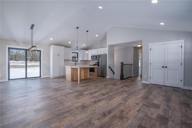 kitchen featuring white cabinetry, stainless steel appliances, a kitchen island, hanging light fixtures, and dark wood-type flooring