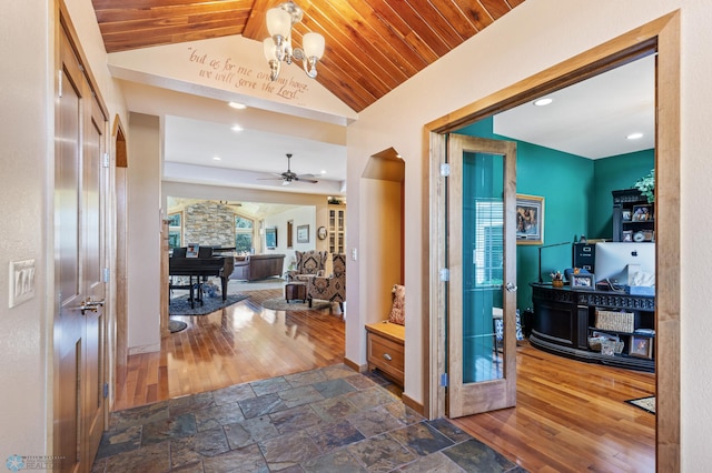hall featuring arched walkways, wooden ceiling, a notable chandelier, vaulted ceiling, and stone tile flooring