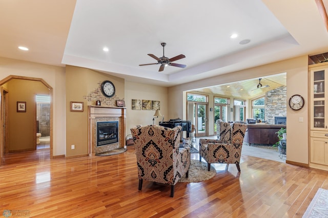 living area featuring a premium fireplace, light wood-type flooring, and a raised ceiling