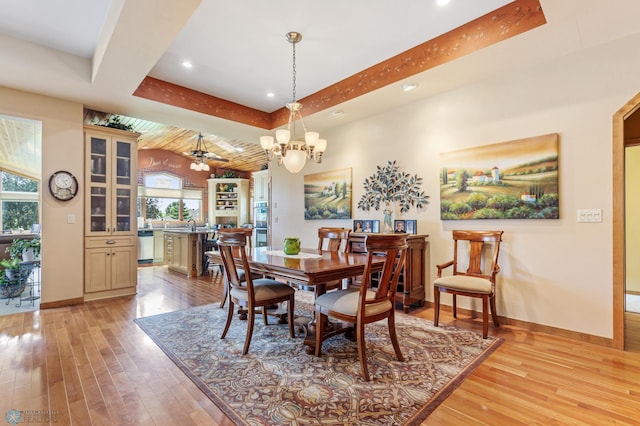 dining space featuring light wood-style flooring, baseboards, beam ceiling, and ceiling fan with notable chandelier