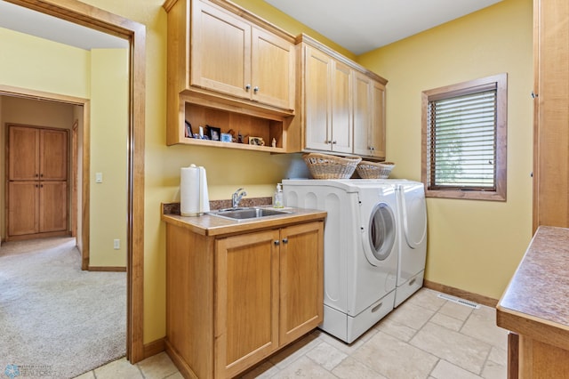 washroom featuring light colored carpet, a sink, baseboards, cabinet space, and washing machine and clothes dryer