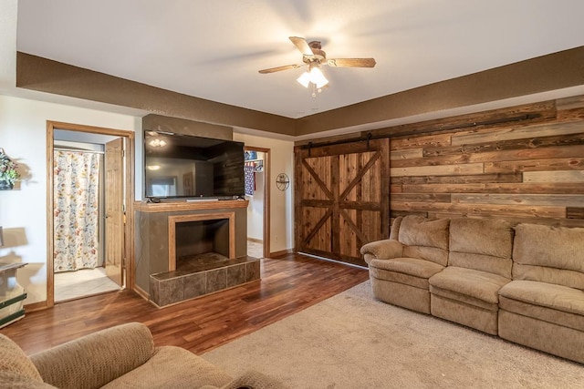 living room featuring a barn door, wood-type flooring, and ceiling fan