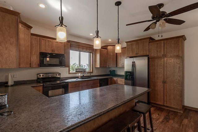 kitchen featuring a breakfast bar area, black appliances, dark wood-type flooring, sink, and ceiling fan