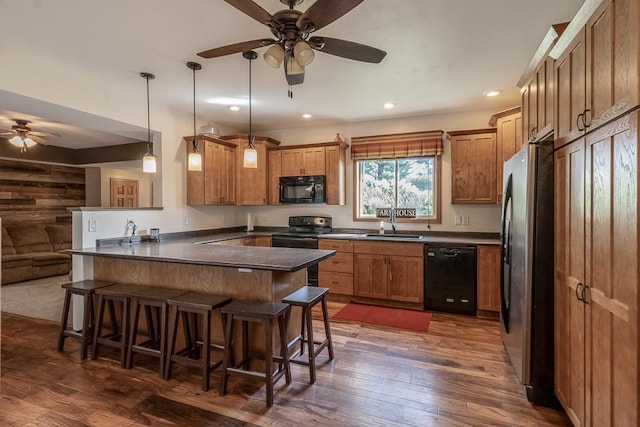 kitchen featuring a kitchen bar, black appliances, ceiling fan, and dark hardwood / wood-style flooring