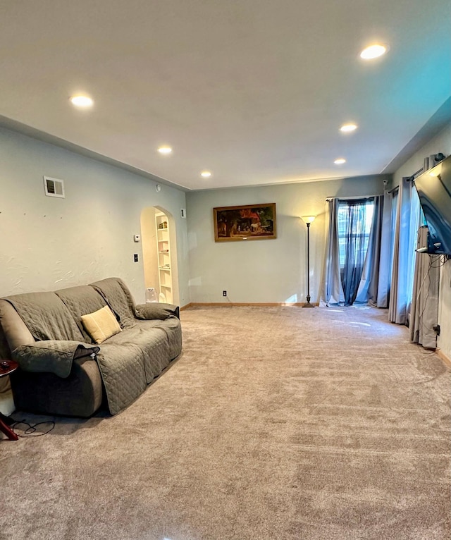 carpeted living room with visible vents, arched walkways, and recessed lighting