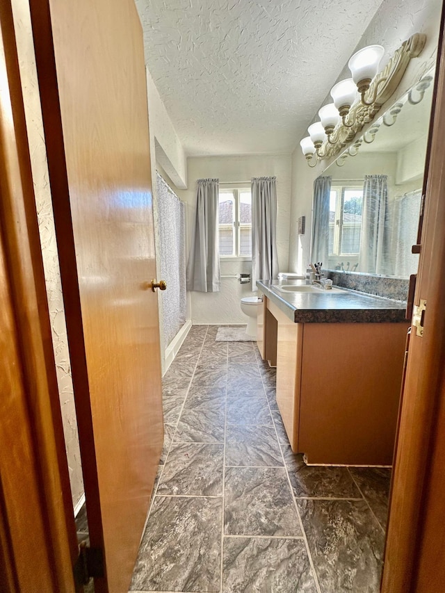 bathroom with toilet, an inviting chandelier, a textured ceiling, and vanity