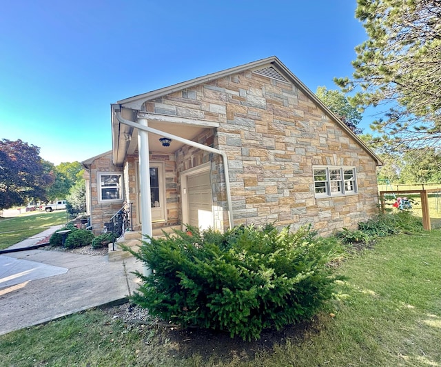 view of side of property featuring stone siding, a lawn, and an attached garage