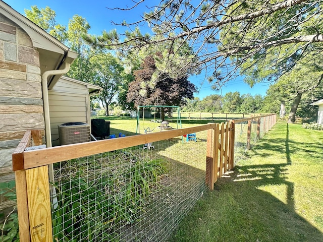 view of yard featuring central AC and fence