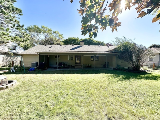 rear view of house featuring a yard, a chimney, and central AC unit