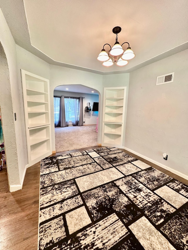 interior space featuring arched walkways, baseboards, visible vents, and built in features