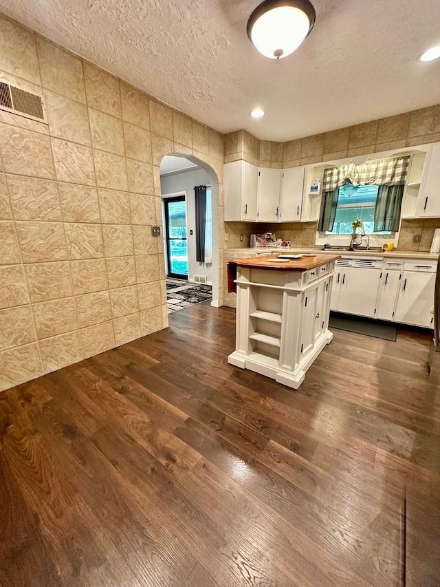 kitchen featuring arched walkways, open shelves, and white cabinetry