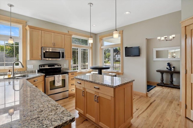 kitchen with a center island, light hardwood / wood-style floors, appliances with stainless steel finishes, and hanging light fixtures