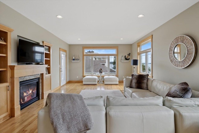 living room featuring built in shelves, light hardwood / wood-style floors, and a high end fireplace