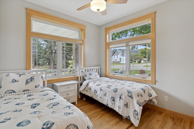 bedroom featuring ceiling fan, light hardwood / wood-style floors, and multiple windows