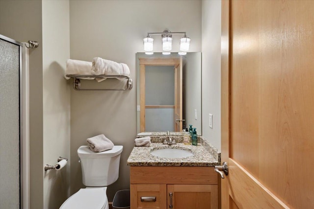 bathroom featuring vanity, a shower with shower door, and toilet