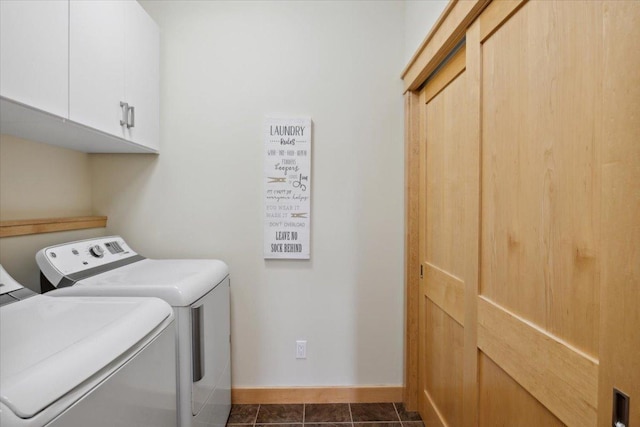 washroom with cabinets, dark tile patterned floors, and washing machine and dryer