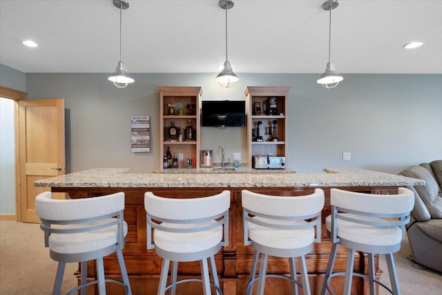 bar with light stone countertops, light colored carpet, and hanging light fixtures