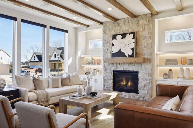 living room featuring beam ceiling and a stone fireplace