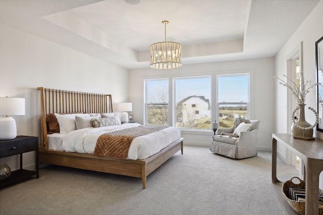 bedroom featuring carpet floors, a chandelier, and a tray ceiling