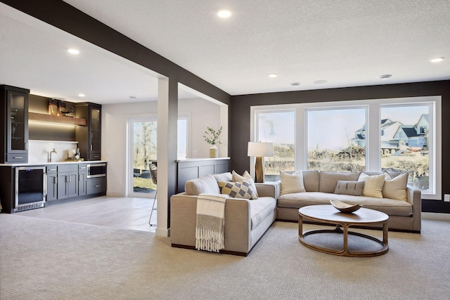 carpeted living room featuring sink, a textured ceiling, and wine cooler