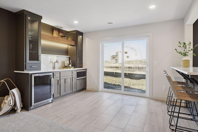 bar featuring sink, beverage cooler, and stainless steel microwave