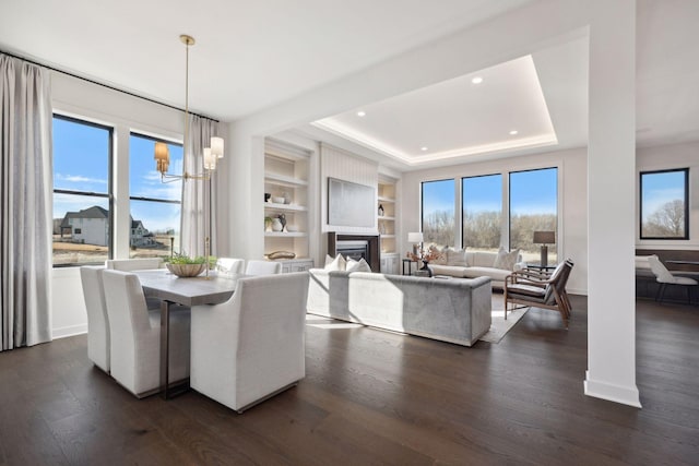 dining area featuring dark wood-style floors, a tray ceiling, a wealth of natural light, and a notable chandelier